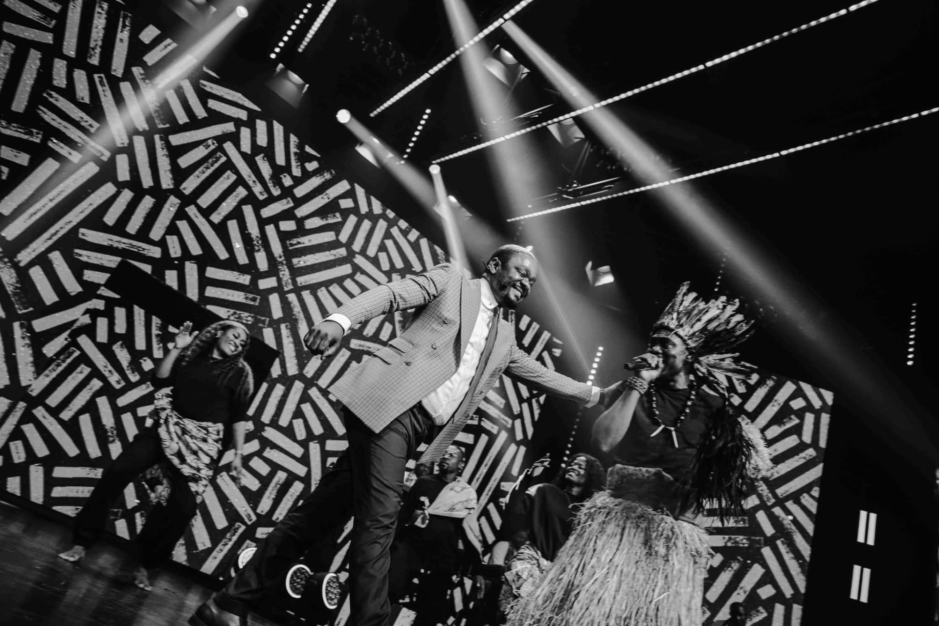 Scène Maajabu en noir et blanc, faisceaux de lumière et danseurs