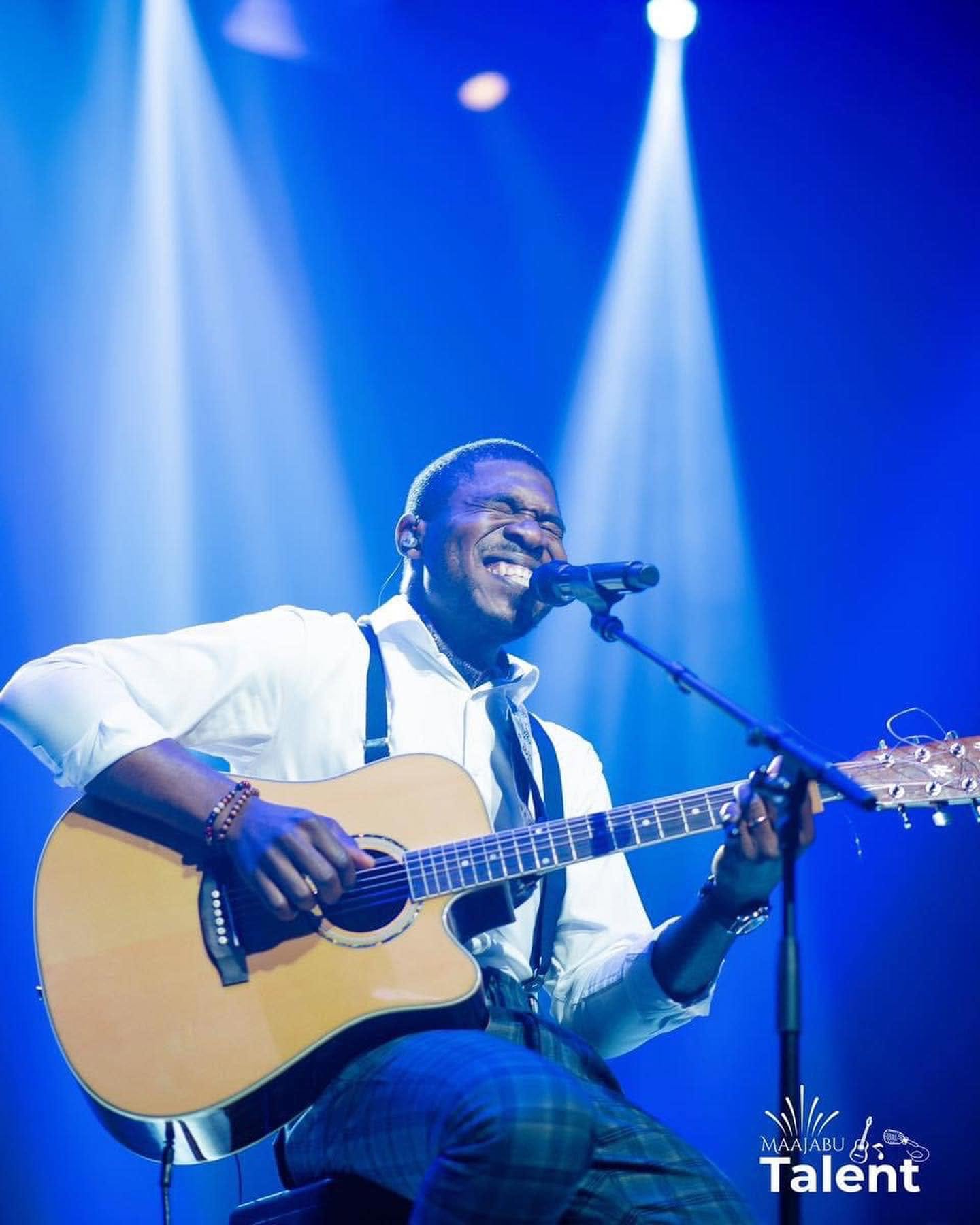 Kalenga 1er en finale de Maajabu Talent, guitare à la main sous les lumières bleues