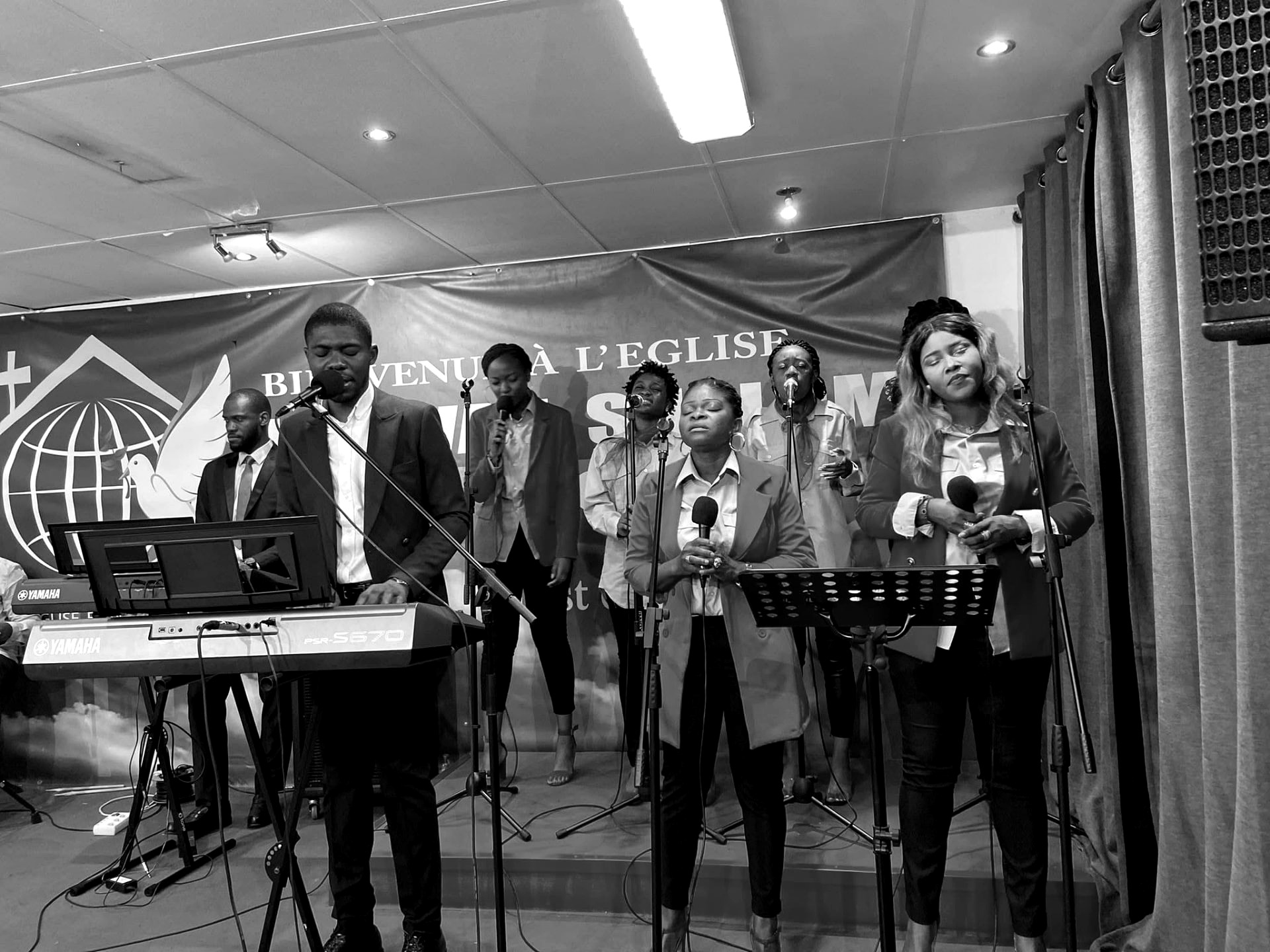 Kalenga 1er dirigeant la chorale au clavier pendant le culte, noir et blanc