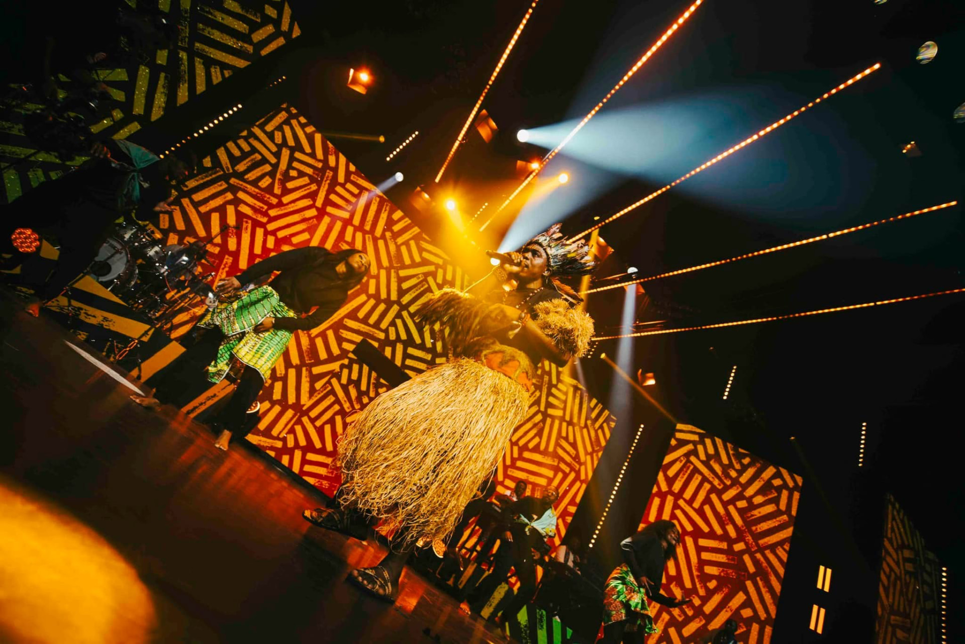 Scène Maajabu illuminée d'orange, danseurs en tenue traditionnelle