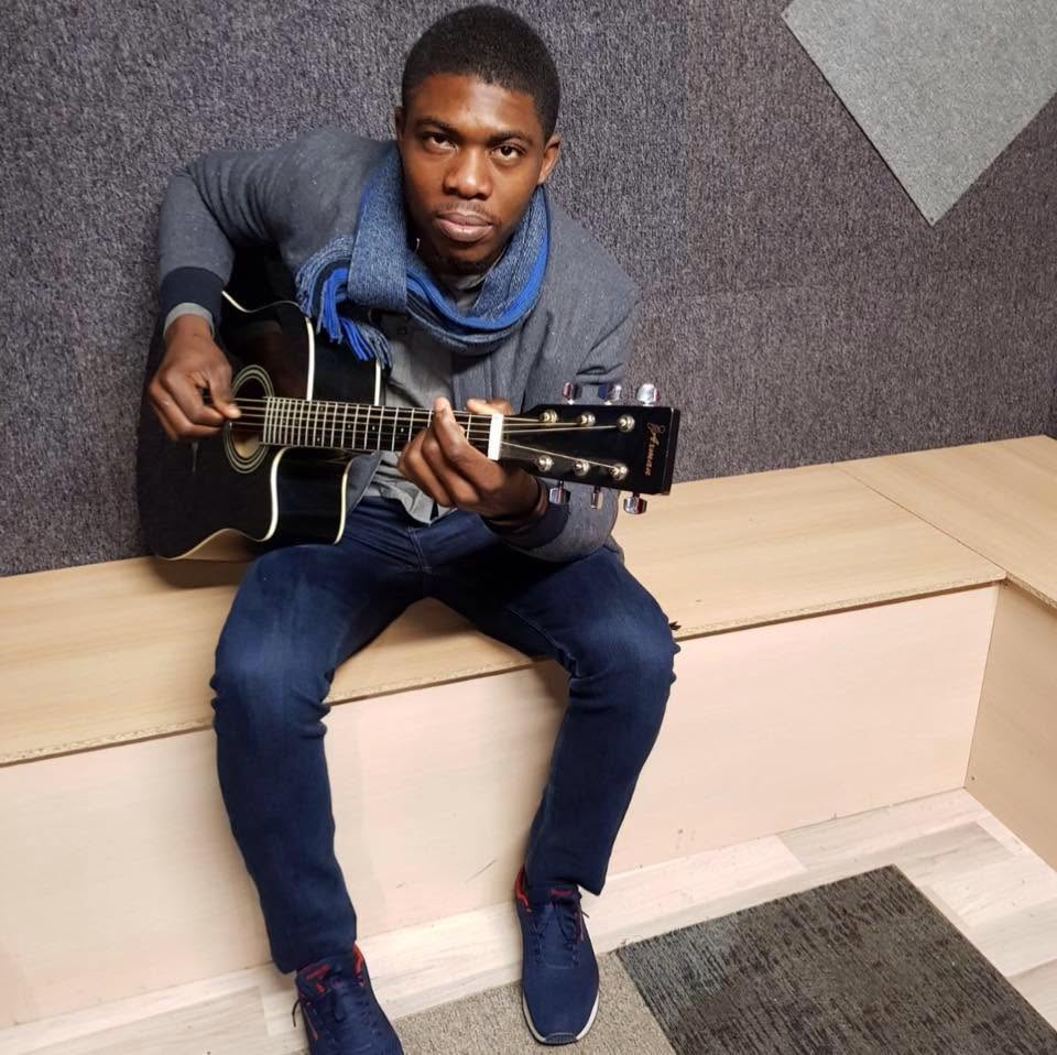 Kalenga 1er assis en coulisses, guitare sèche à la main